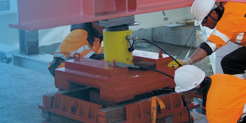 Three workers are operating the jack equipment with EXACT-FLEX jack hoses.